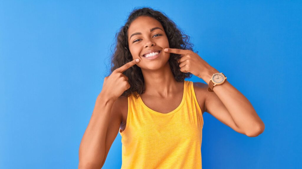 woman pointing to smile, asking Why do my gums show when I smile